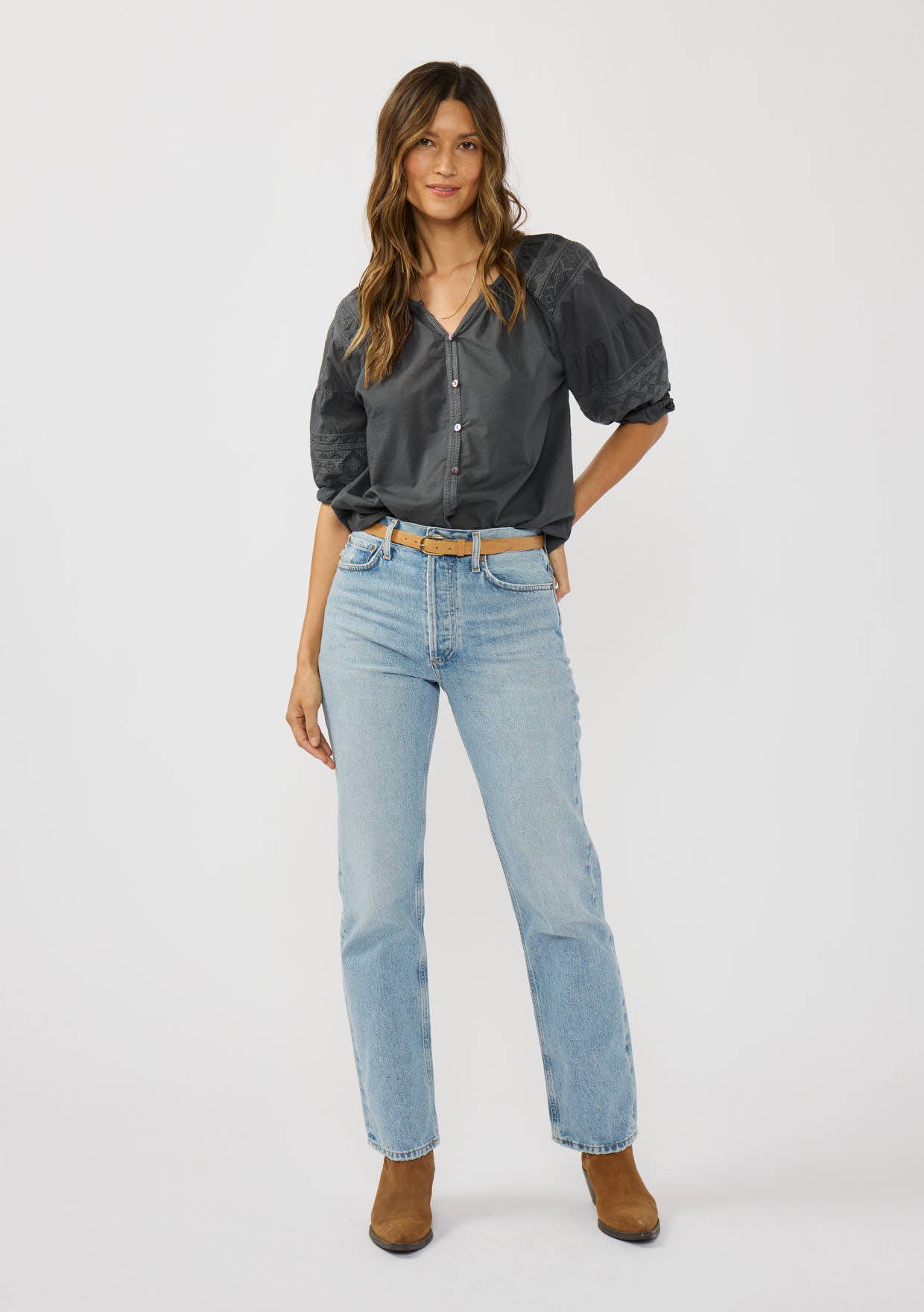 Woman wearing a black Short Raglan Puff Sleeve Button Down Top paired with light blue jeans and brown ankle boots.