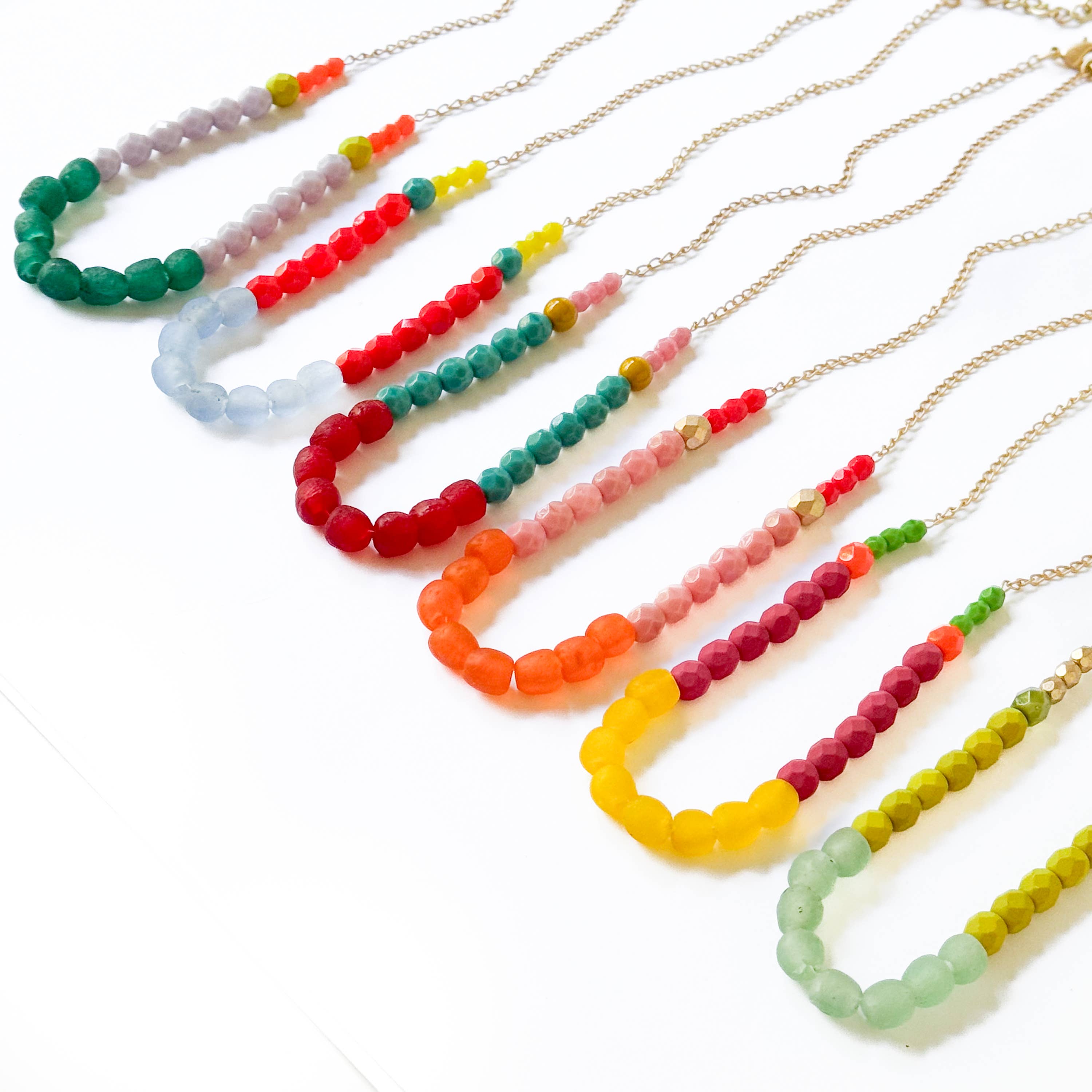 Multicolor Recycled African Glass And Mixed Bead Necklace with vibrant beads on delicate gold chains arranged in a row
