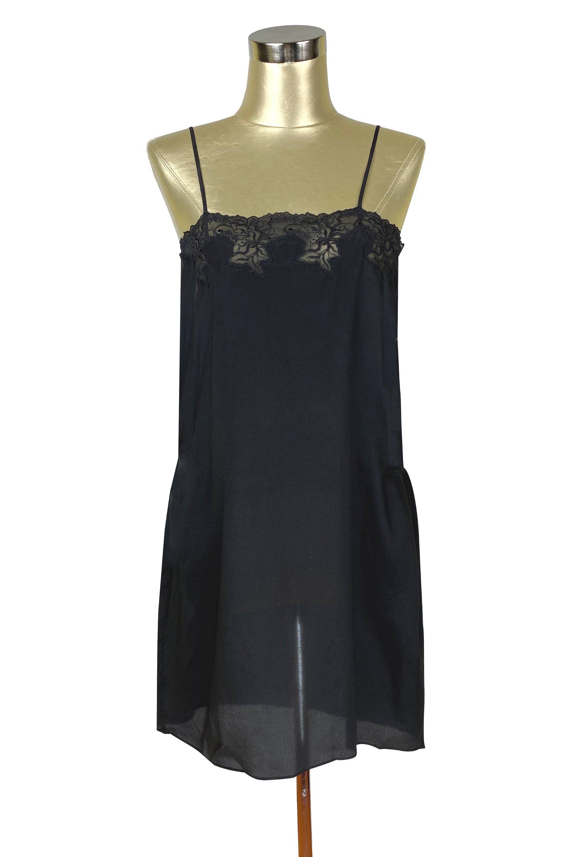 The Colette Tunic Dress - Kohl in black with delicate lace trim and thin straps on a gold mannequin bust