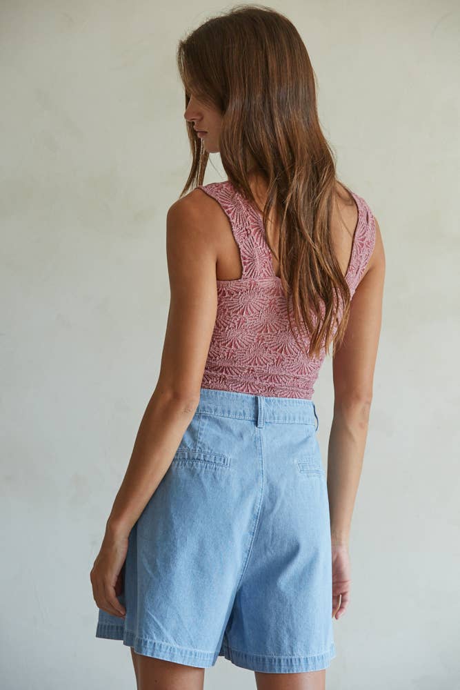 A woman with long brown hair stands facing away, wearing the By Together Knit Modal Nylon Spandex Seamless Jacquard Tank and high-waisted light blue denim shorts against a light neutral background.