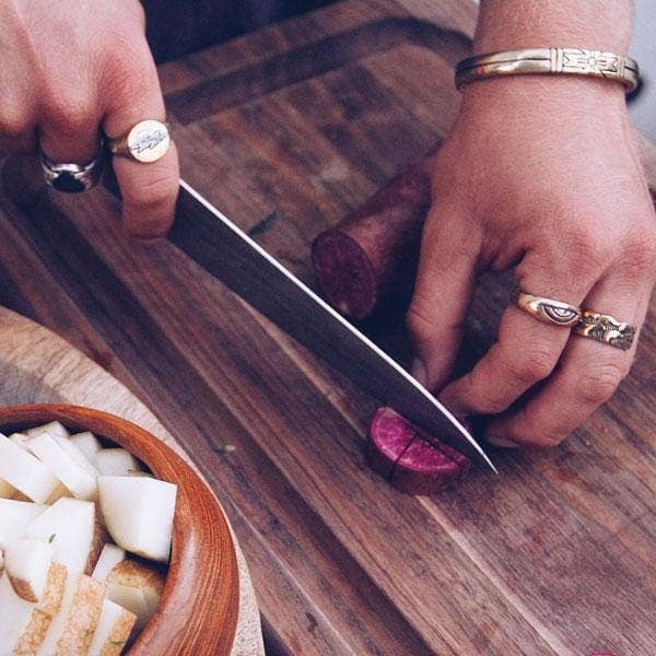 Close-up of hands wearing Medicine Wheel Cuff || Men and rings while slicing purple root vegetable on wooden board