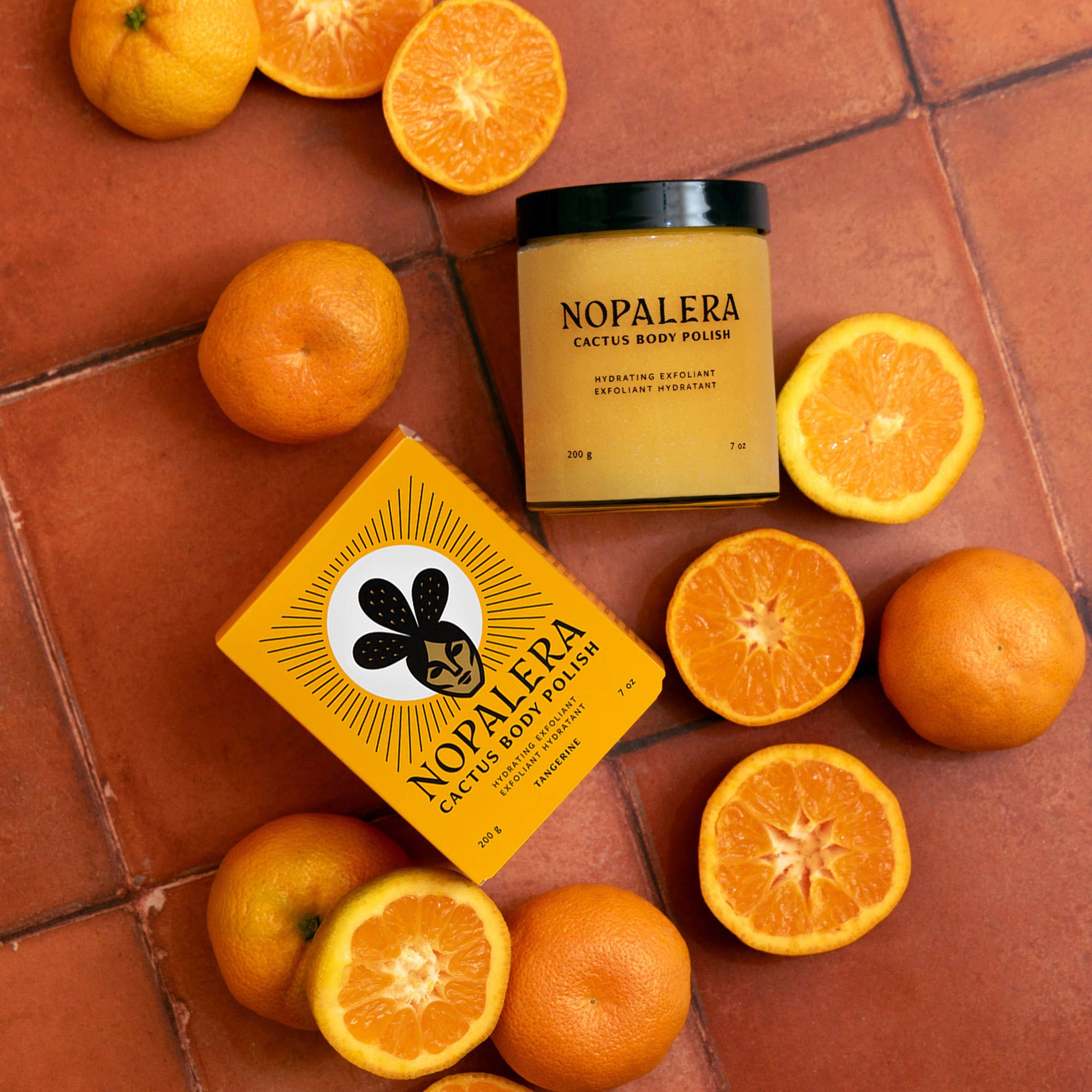 Tangerine Cactus Body Polish with citrus fruits on terracotta tiles showcases bright, refreshing skincare packaging and product.