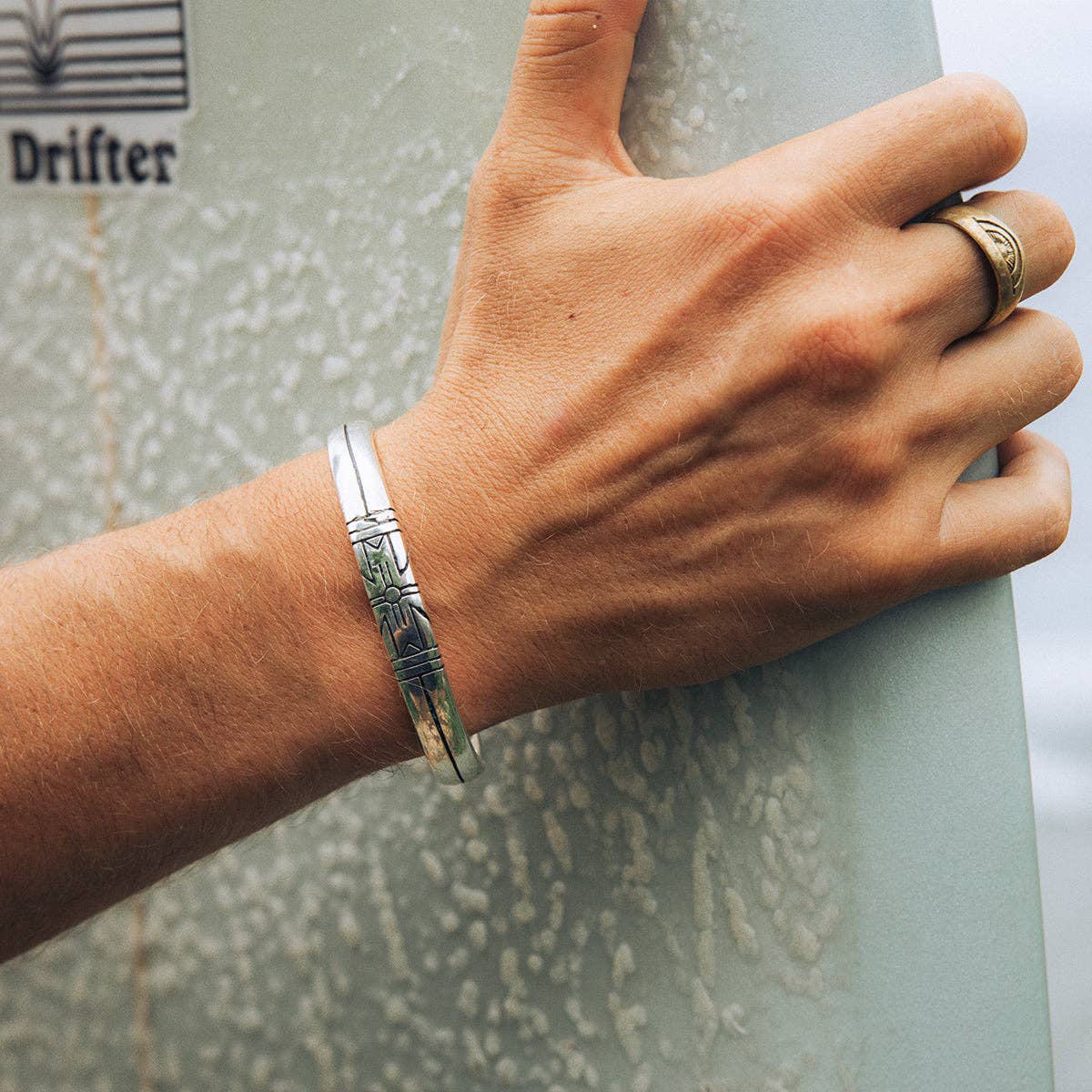 Medicine Wheel Cuff || Men worn on wrist with engraved detailed design in a casual outdoor setting.