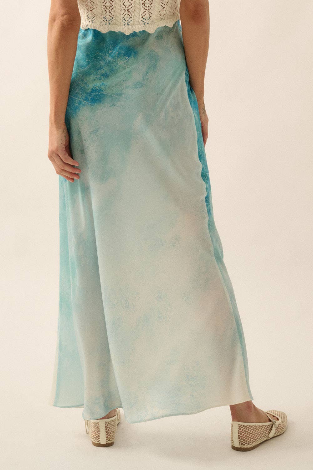 Model wearing a flowing Tie Dye-Print Satin Bias-Cut Maxi Skirt in soft blue and white tones with a crochet top.