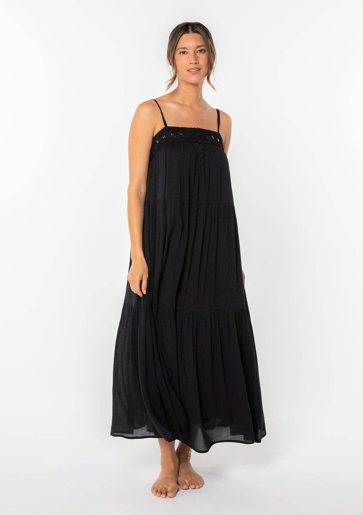 Woman wearing a flowing black Bohemian Crochet Tiered Maxi Dress with thin straps and crochet detailing on top.