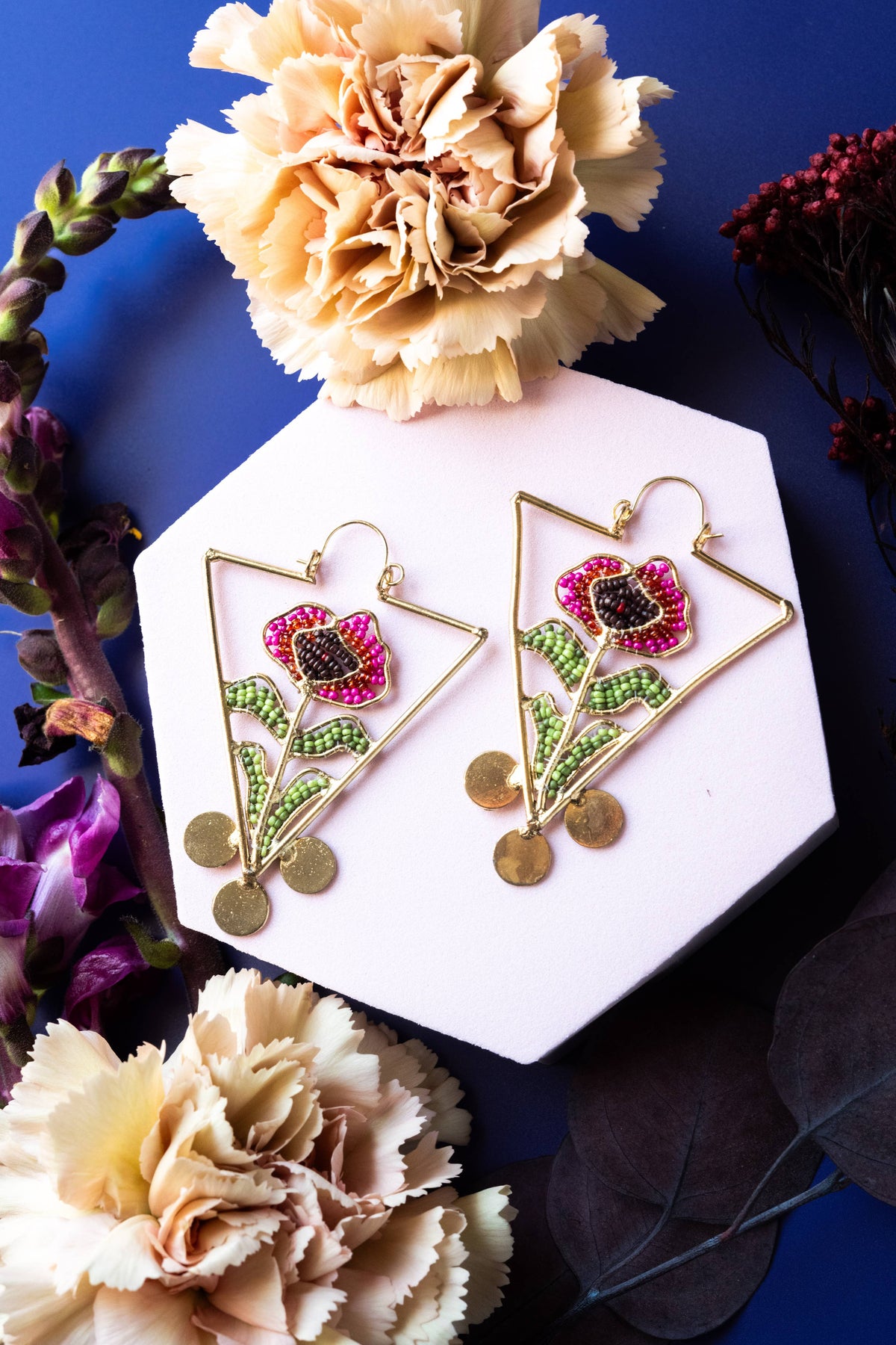 Blooming Reverie Hoops colorful floral embroidered geometric drop earrings with gold discs displayed among dried flowers