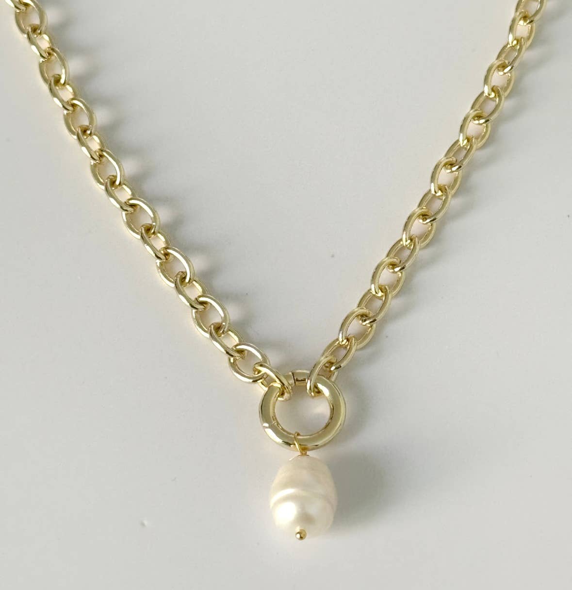 The Soizic Necklace by Tramps+Thieves features an 18K gold-plated chain with medium links and a single white baroque pearl charm on a circular ring, shown against a white background for a chic Los Angeles-inspired look.