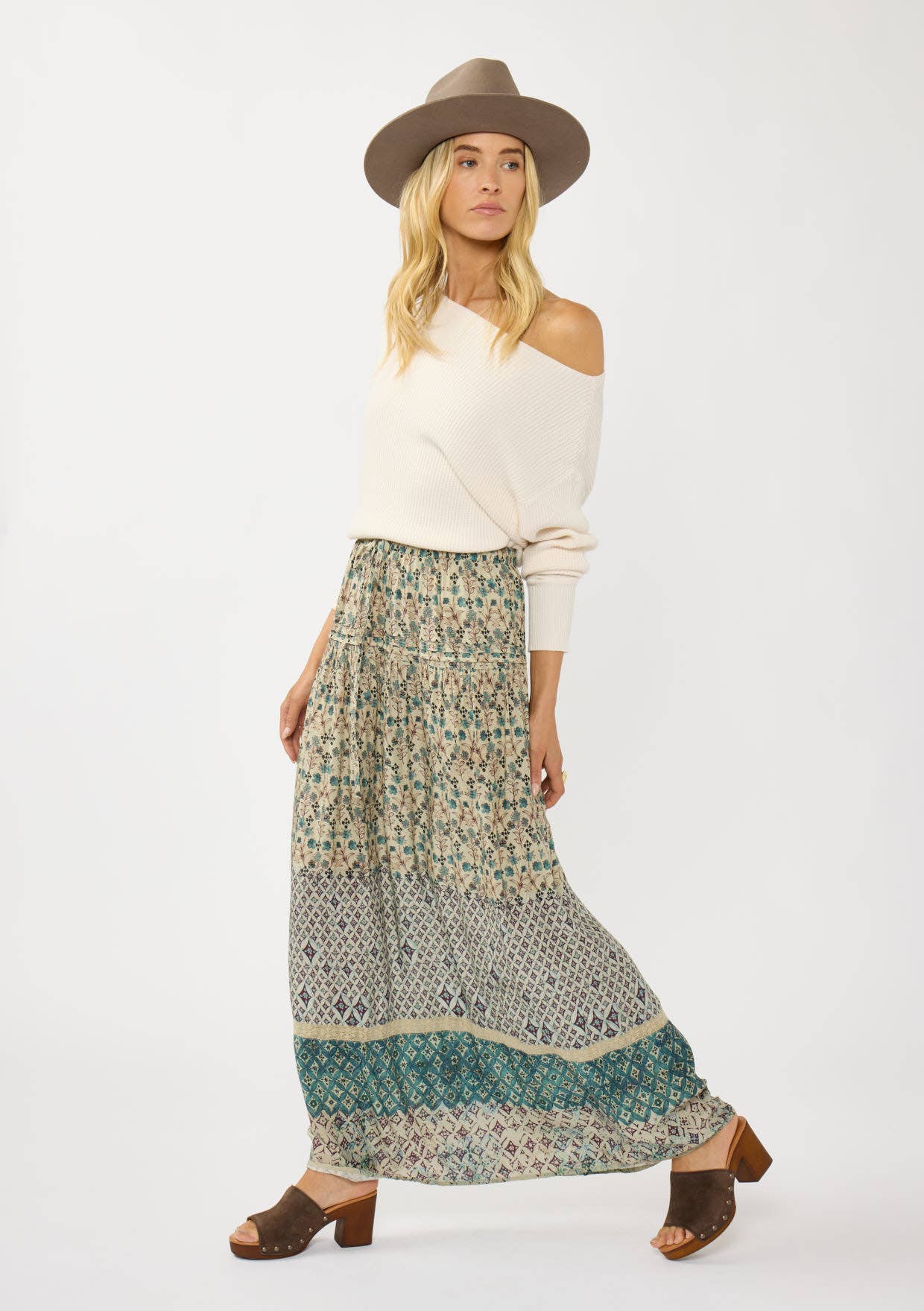 Woman wearing Floral and Tribal Border Drawstring Maxi Skirt with off-shoulder sweater, hat, and heeled sandals.