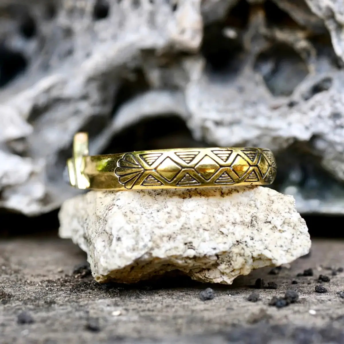 Hold Space Cuff brass bracelet with engraved geometric patterns resting on textured stone surface.