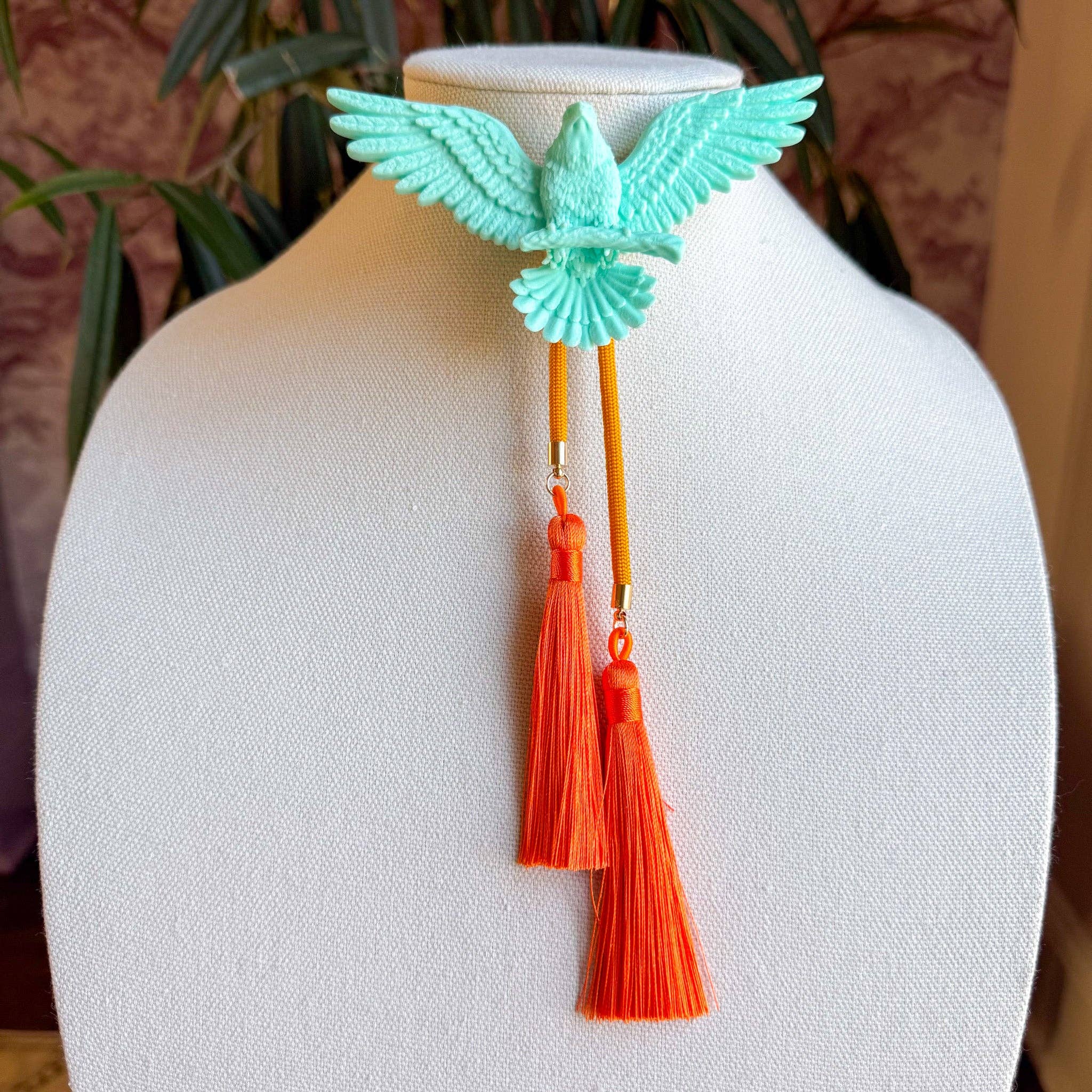 Eagle Bolo Turquoise with Golden Yellow & Orange featuring a turquoise eagle and vibrant yellow and orange tassels on display bust