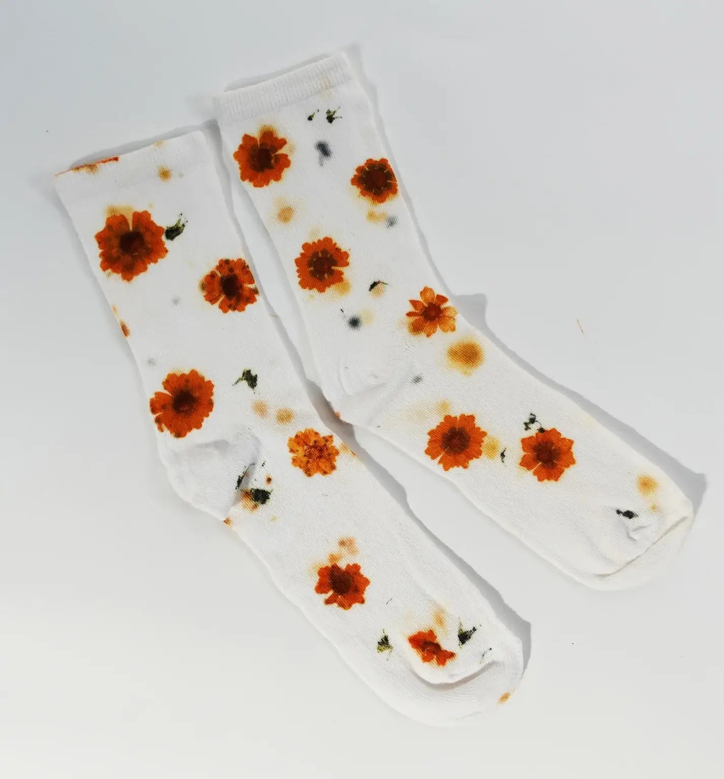 White socks with orange floral print and green accents, named Flower Power Cotton Crew Sock, laid flat on white background