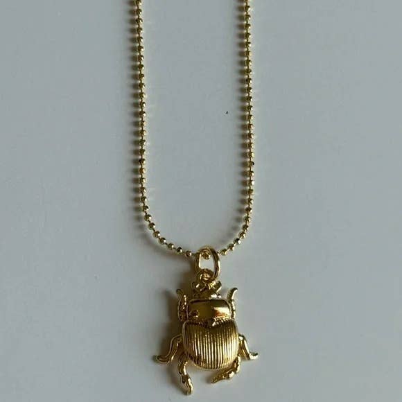 The Tramps+Thieves Scarab Necklace features a gold-filled scarab beetle pendant, showcased elegantly against a plain white background.