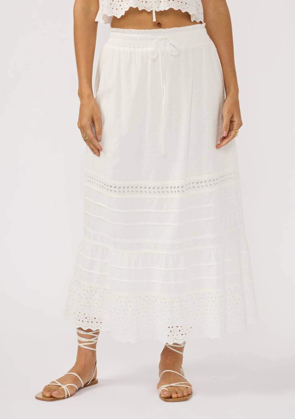 Woman wearing a white Eyelet Hem Pintuck Skirt with drawstring waist and delicate eyelet details at the hem