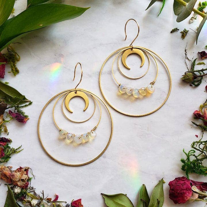 Opal Moon Halo Hoop Earrings with gold crescent moons and opal beads, styled with dried flowers on marble background