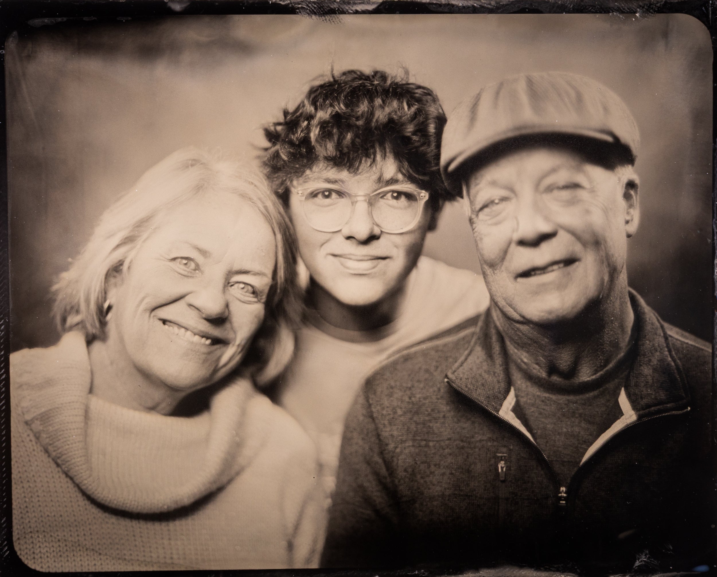 Three generations smiling warmly in a vintage-style black and white portrait photograph
