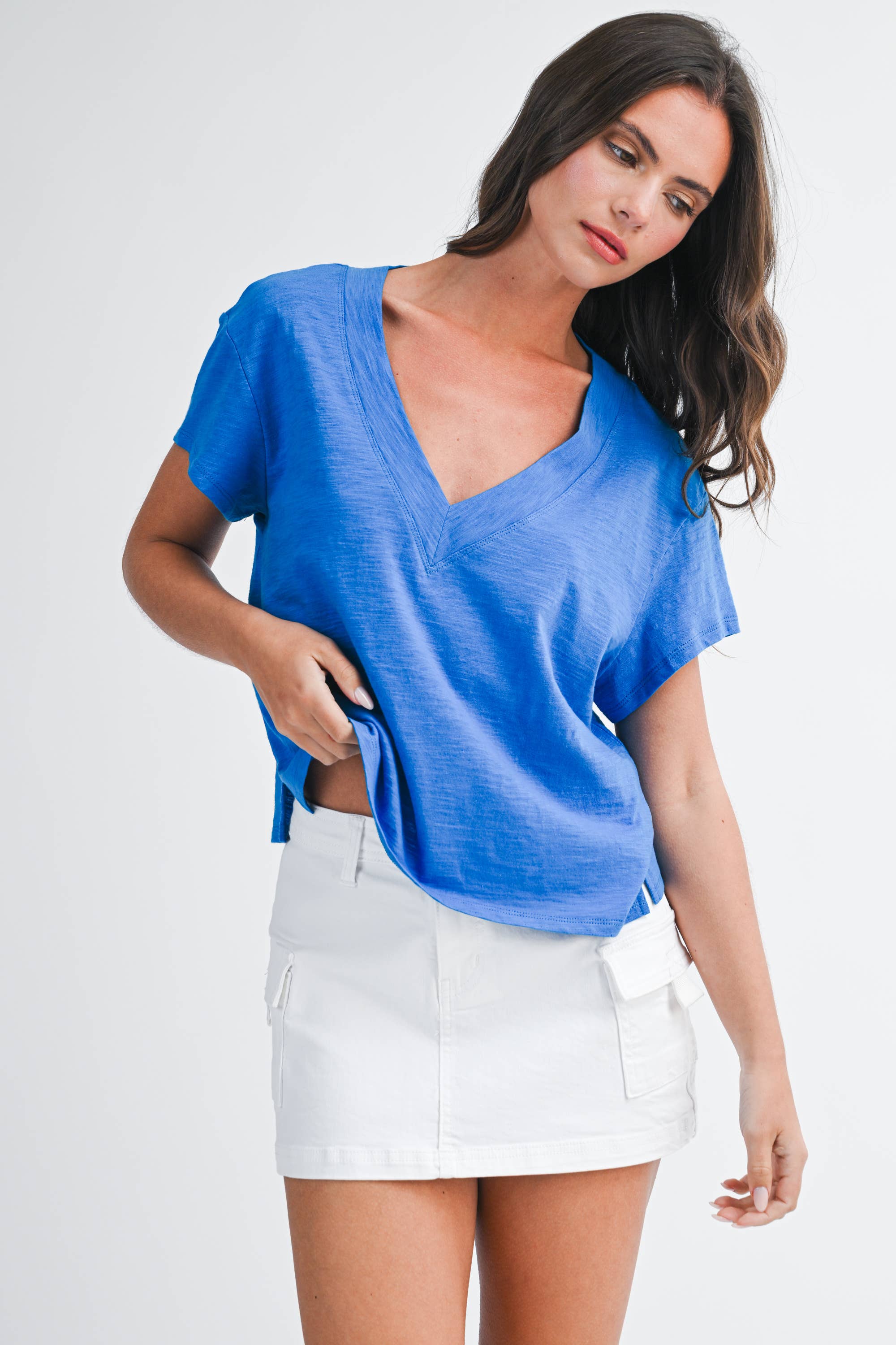 Woman wearing 8281DK Til V-Neck Baby Top: Electric Blue / Contemporary / L with white mini skirt, posing against white background.