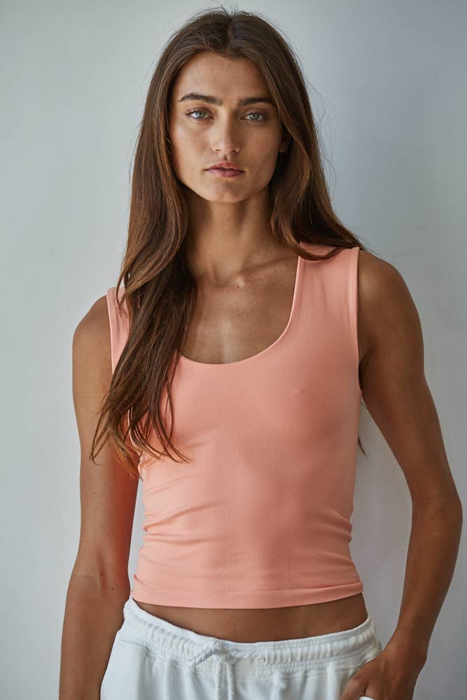 Woman wearing a peach-colored Double Layered Seamless Top paired with white pants against a plain background