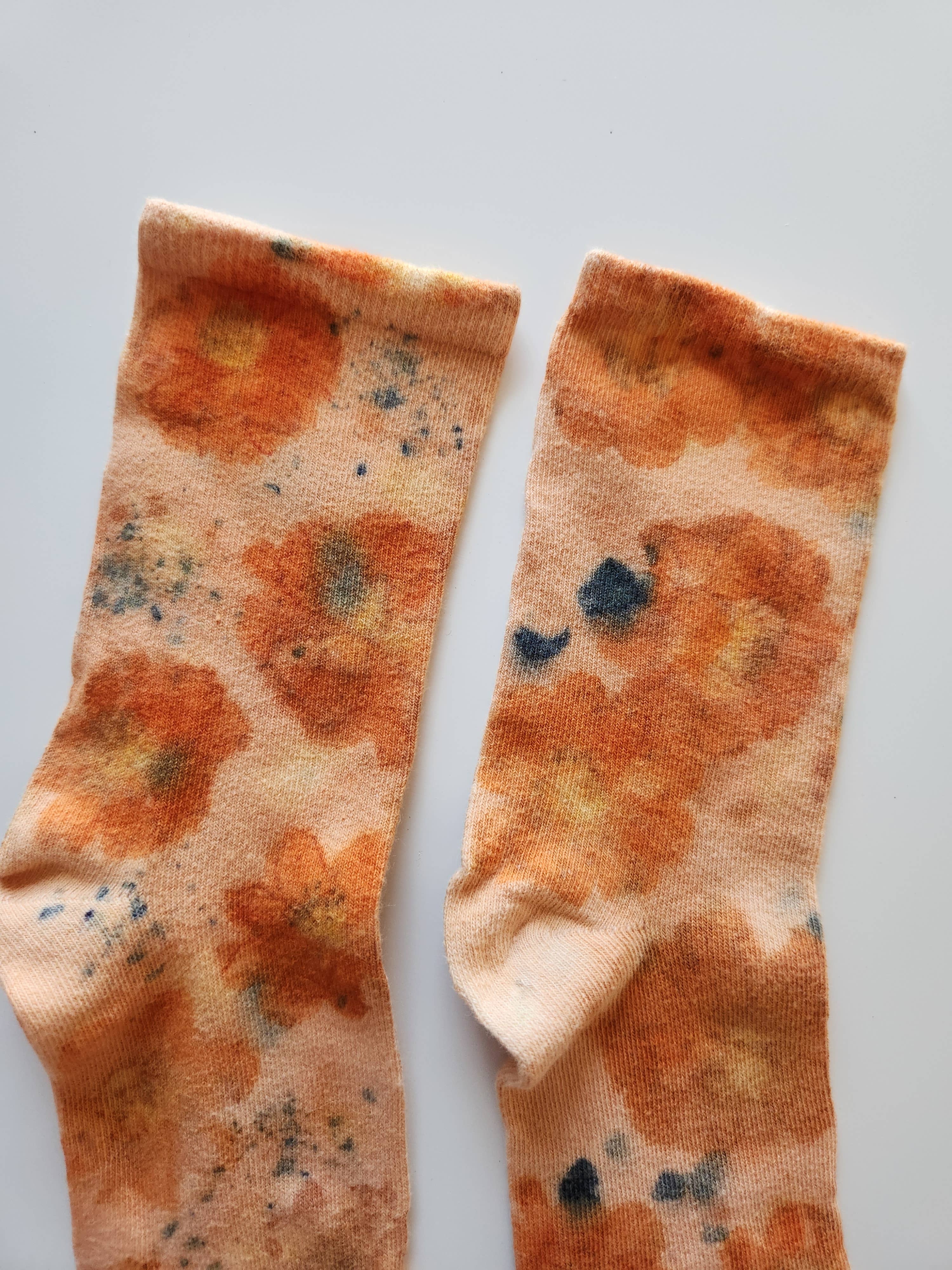 Pair of Flower Power Cotton Crew Sock with orange floral artful graphics on soft fabric background