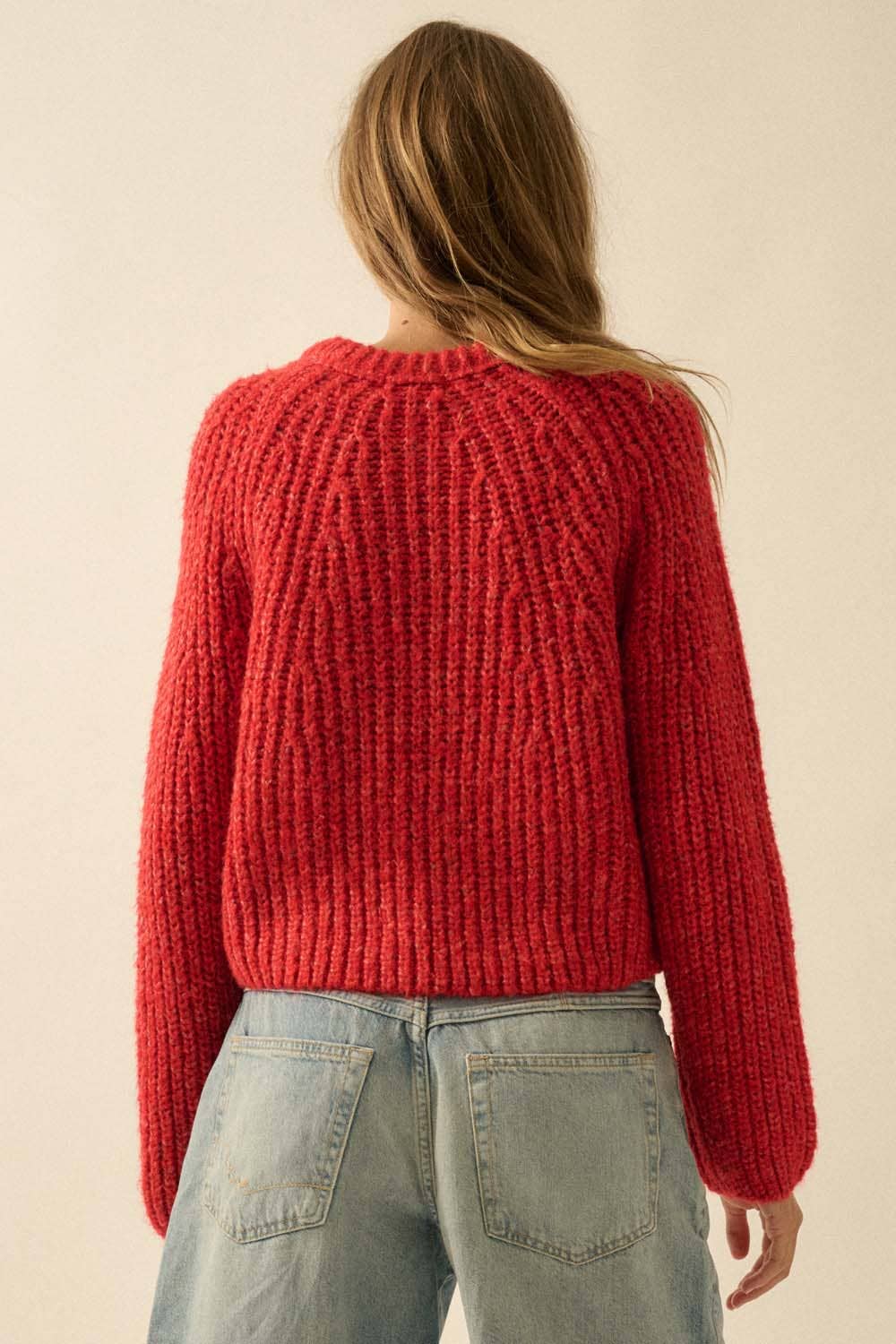 A person with long, light brown hair is shown from the back wearing the Promesa USA Confetti Button-Front Cardigan Sweater in red with light blue jeans, set against a plain, neutral background.