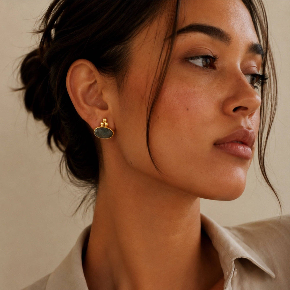 Ayleen Studs gold oval earrings with dark stones worn by a woman
