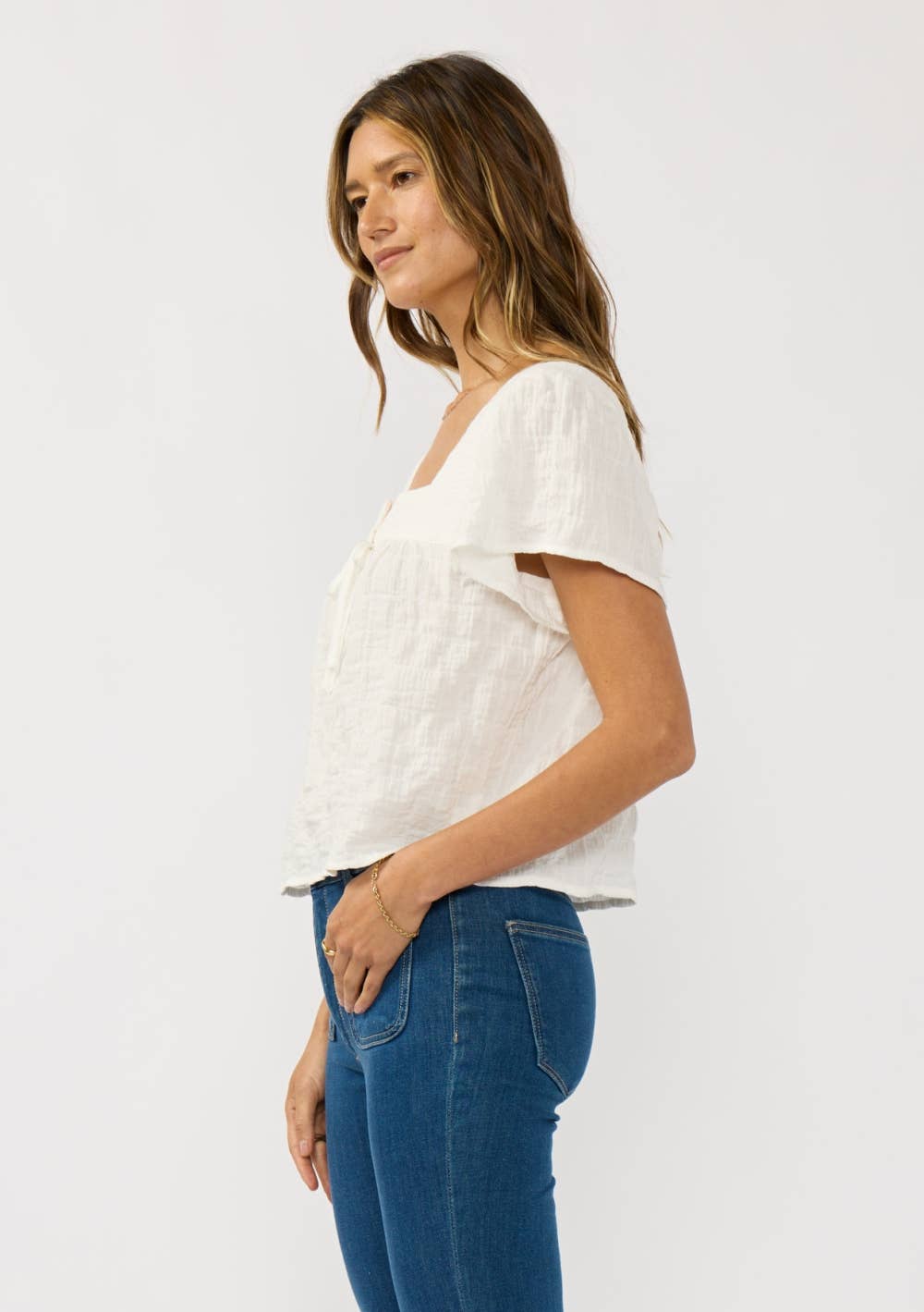 Woman wearing a white Square Neck Puff Sleeve Gauze Top paired with blue jeans against a plain background