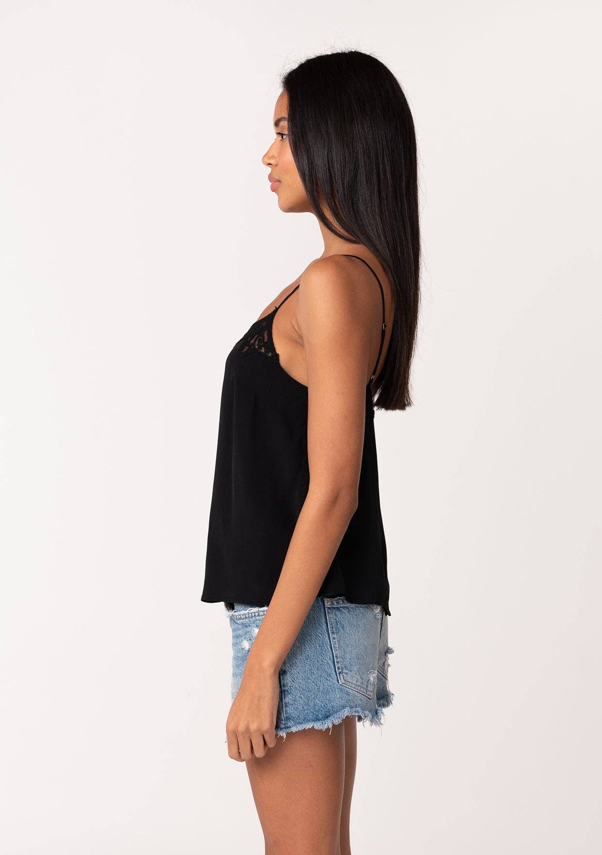 Woman wearing black Button Back Embroidered Lace Cami paired with light blue denim shorts standing in profile