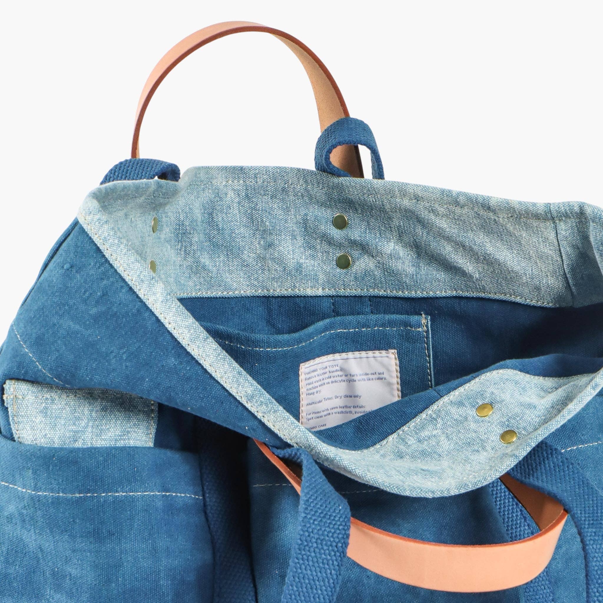 Blue denim backpack with brown leather straps on a light blue background
