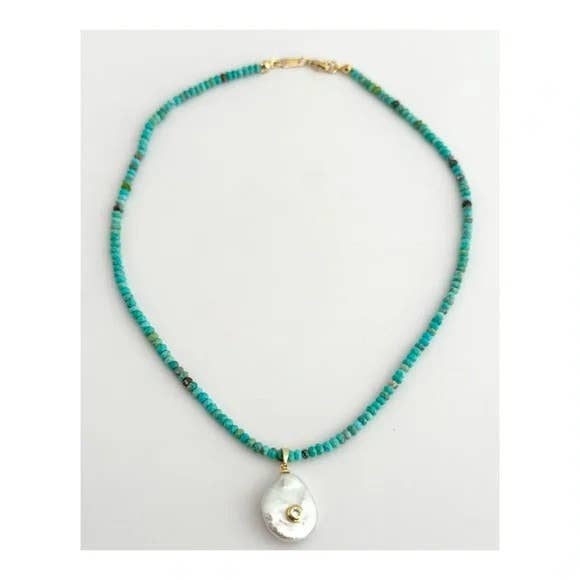 The Mar Turquezza Necklace by Tramps+Thieves features turquoise beads, a striking baroque pearl pendant with gold details, and a gold-filled clasp, showcased on a plain white background.