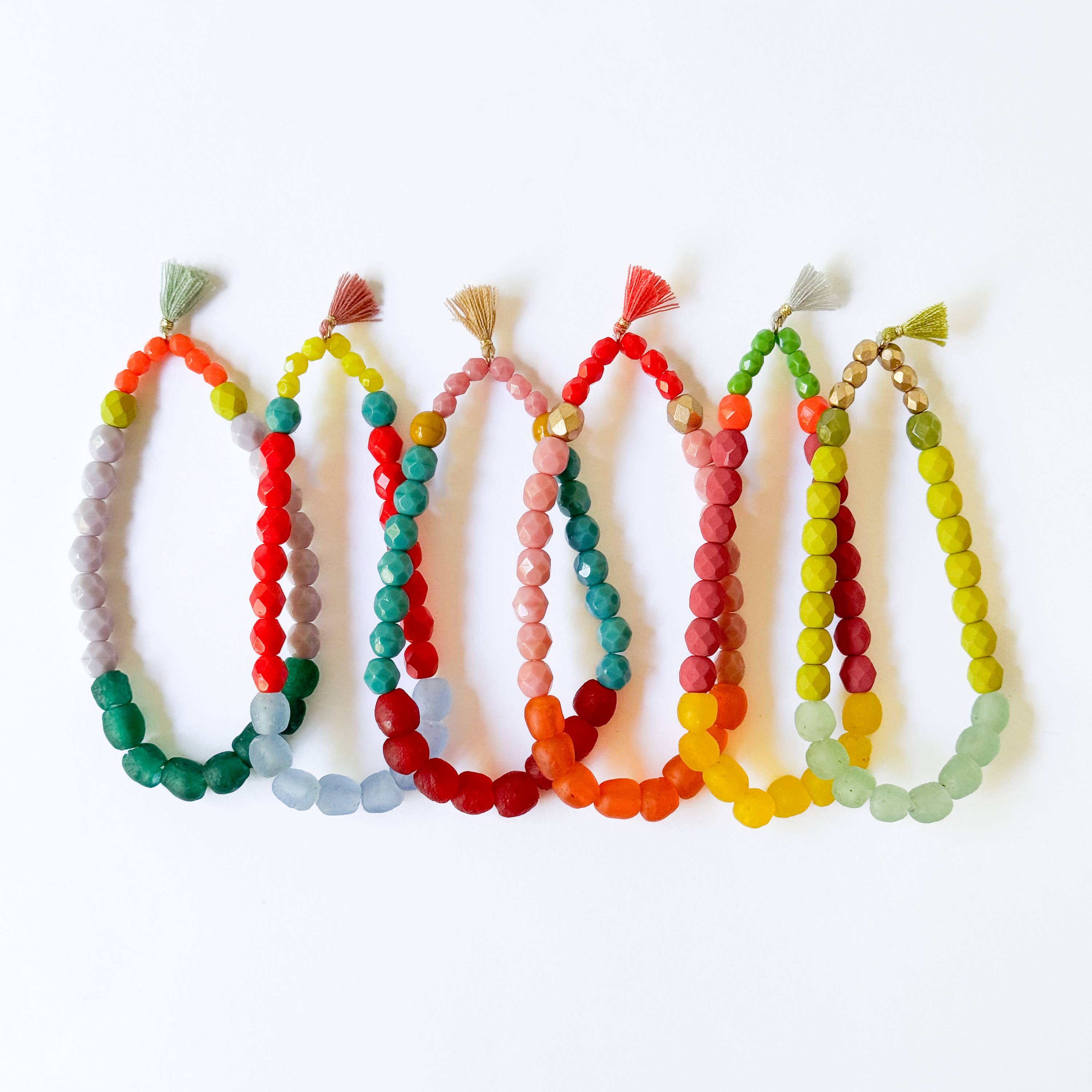 Multicolor Recycled African Glass And Mixed Bead Bracelet in various vibrant color combinations with small tassels on white background