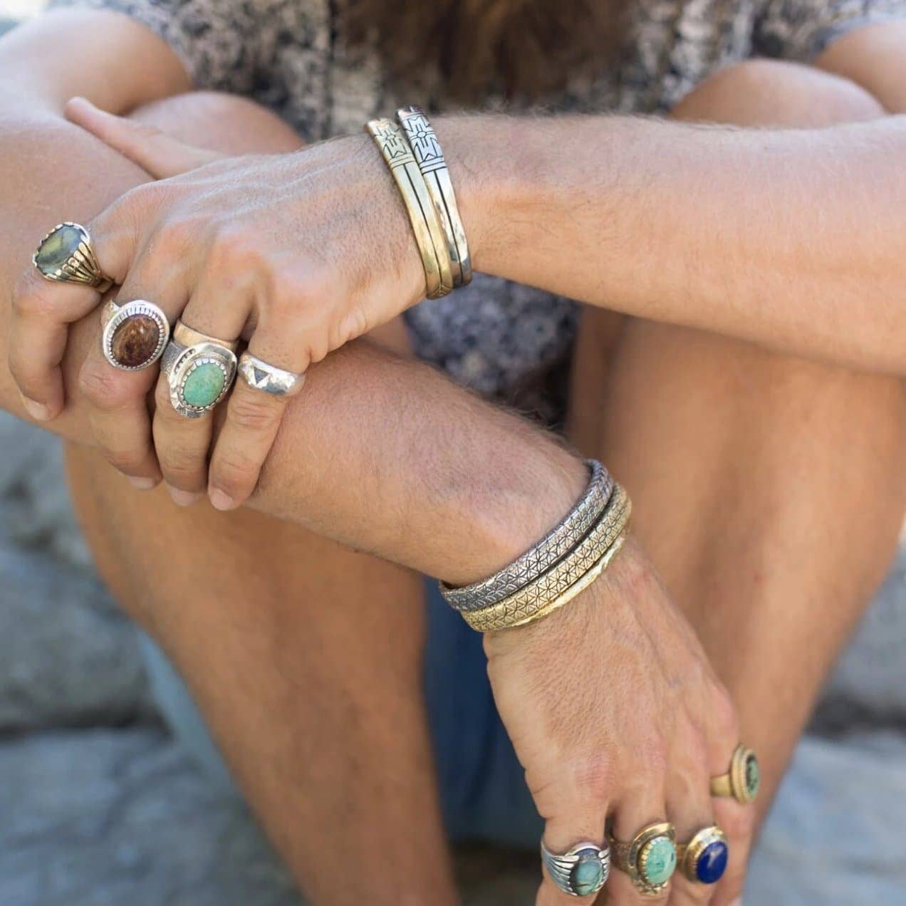 Close-up of hands wearing Medicine Wheel Cuff || Men and various artisan rings with earthy stones and brass details