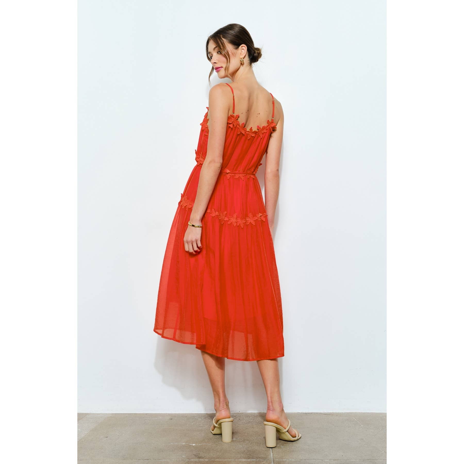 Woman wearing a red dress with thin straps on a white background