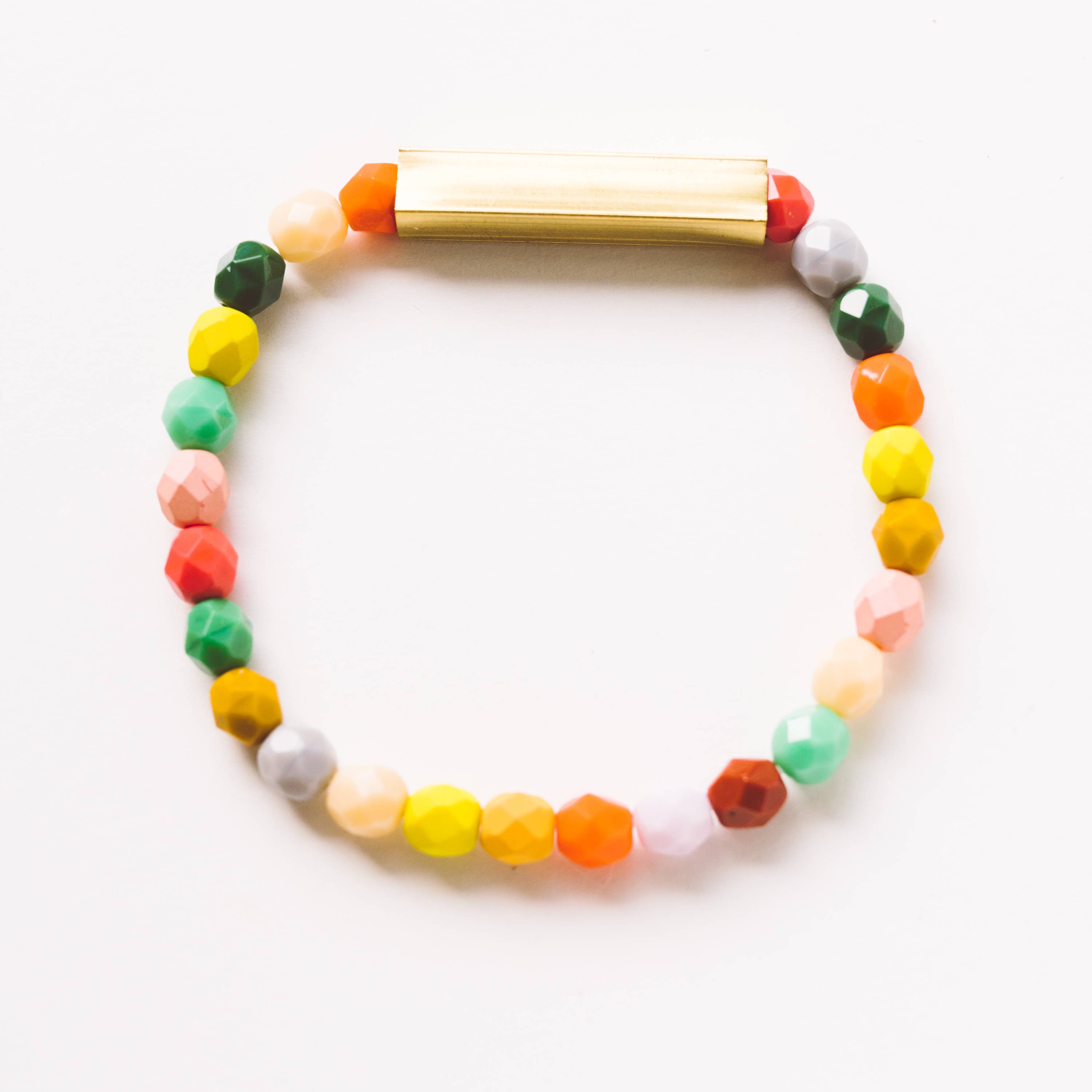 Mixed Beads and Brass Bracelet featuring colorful faceted beads with a smooth brass tube centerpiece on a white background