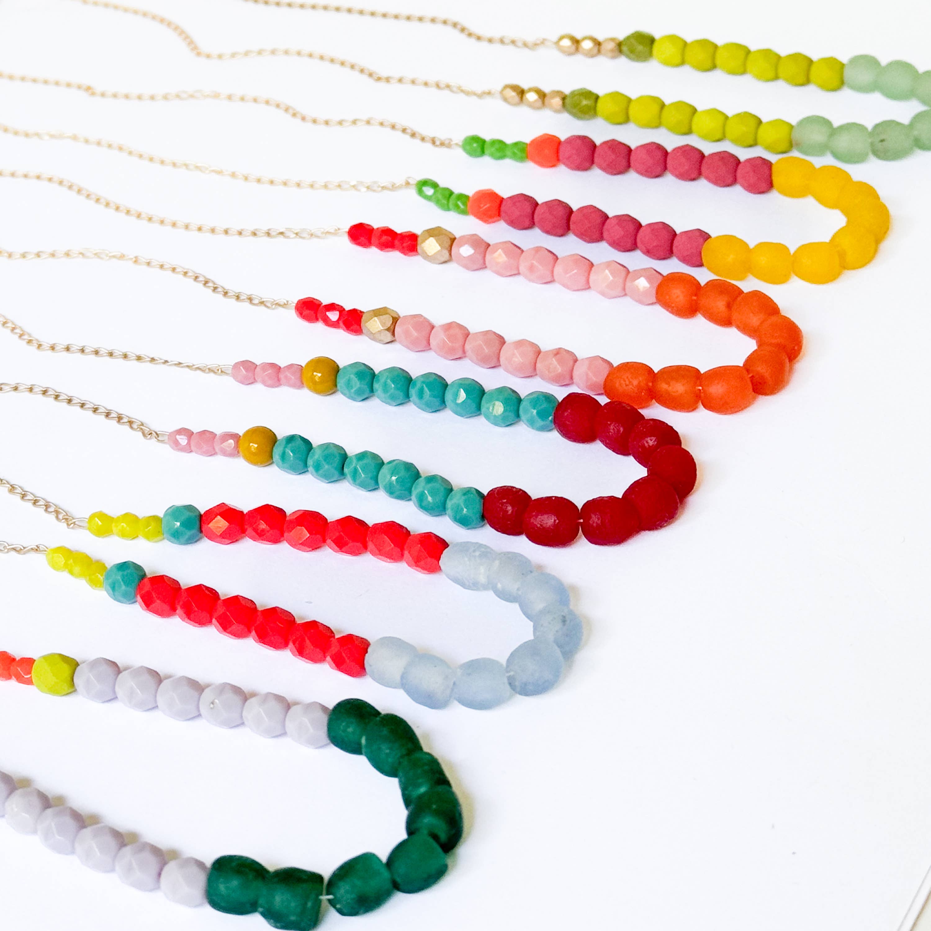 Multicolor Recycled African Glass And Mixed Bead Necklace featuring vibrant handmade beads on delicate gold chains arranged on white background