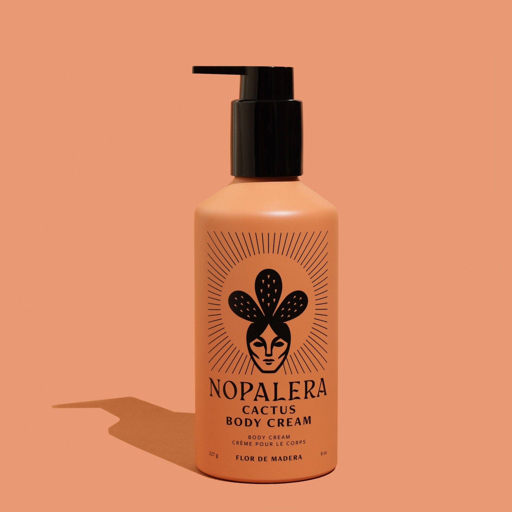 Cactus Body Cream - Flor de Madera in orange bottle with black pump and artistic cactus logo on warm background.
