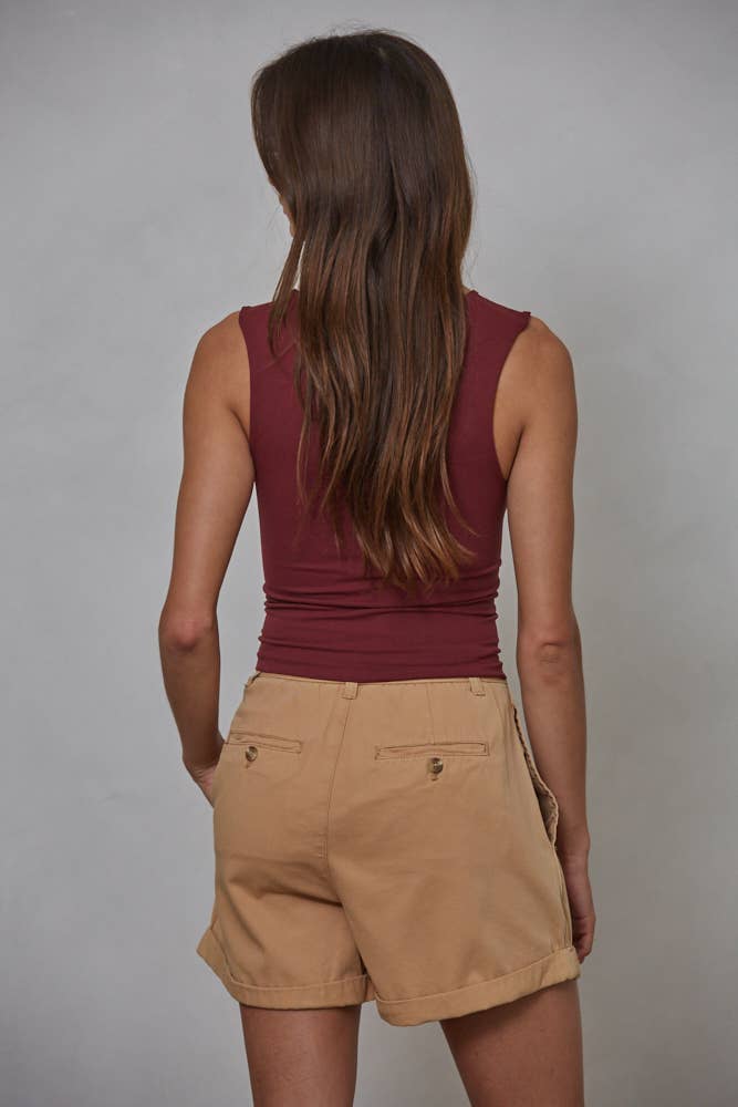 A woman with long brown hair stands with her back to the camera, wearing By Togethers Double Layered Seamless Top in maroon and tan shorts, against a plain light gray background.