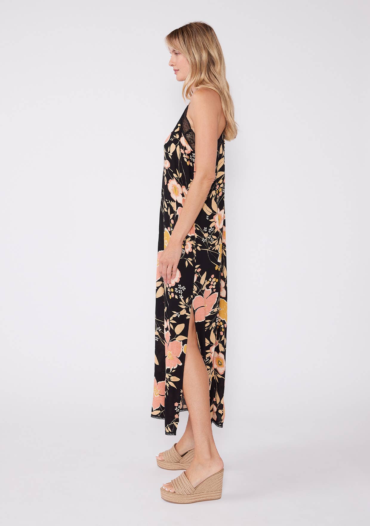 Woman wearing a Floral Lace Trim Racerback Maxi Dress with a black background and peach floral print, side slit visible
