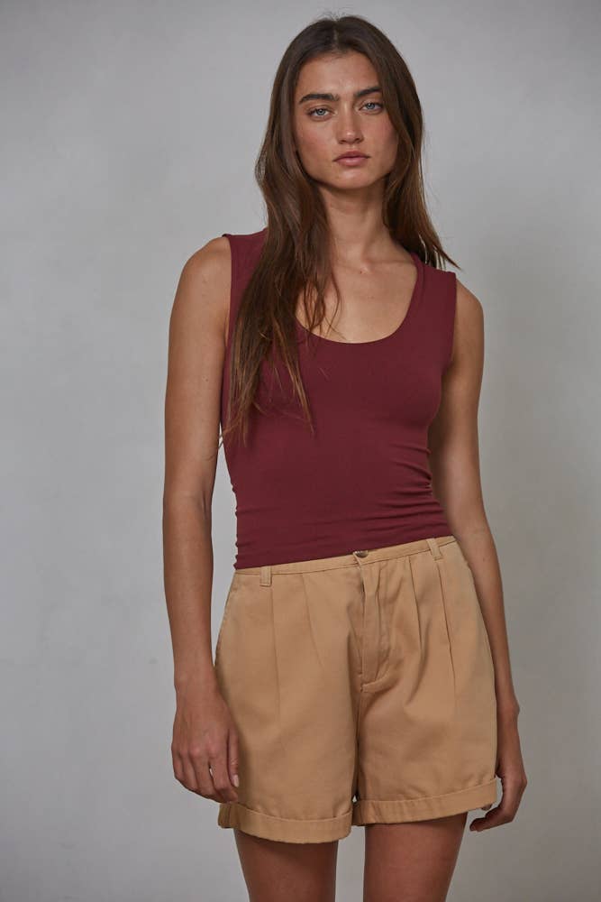 A woman with long brown hair wears the By Together Double Layered Seamless Top in maroon and high-waisted beige shorts, standing against a plain light gray background.