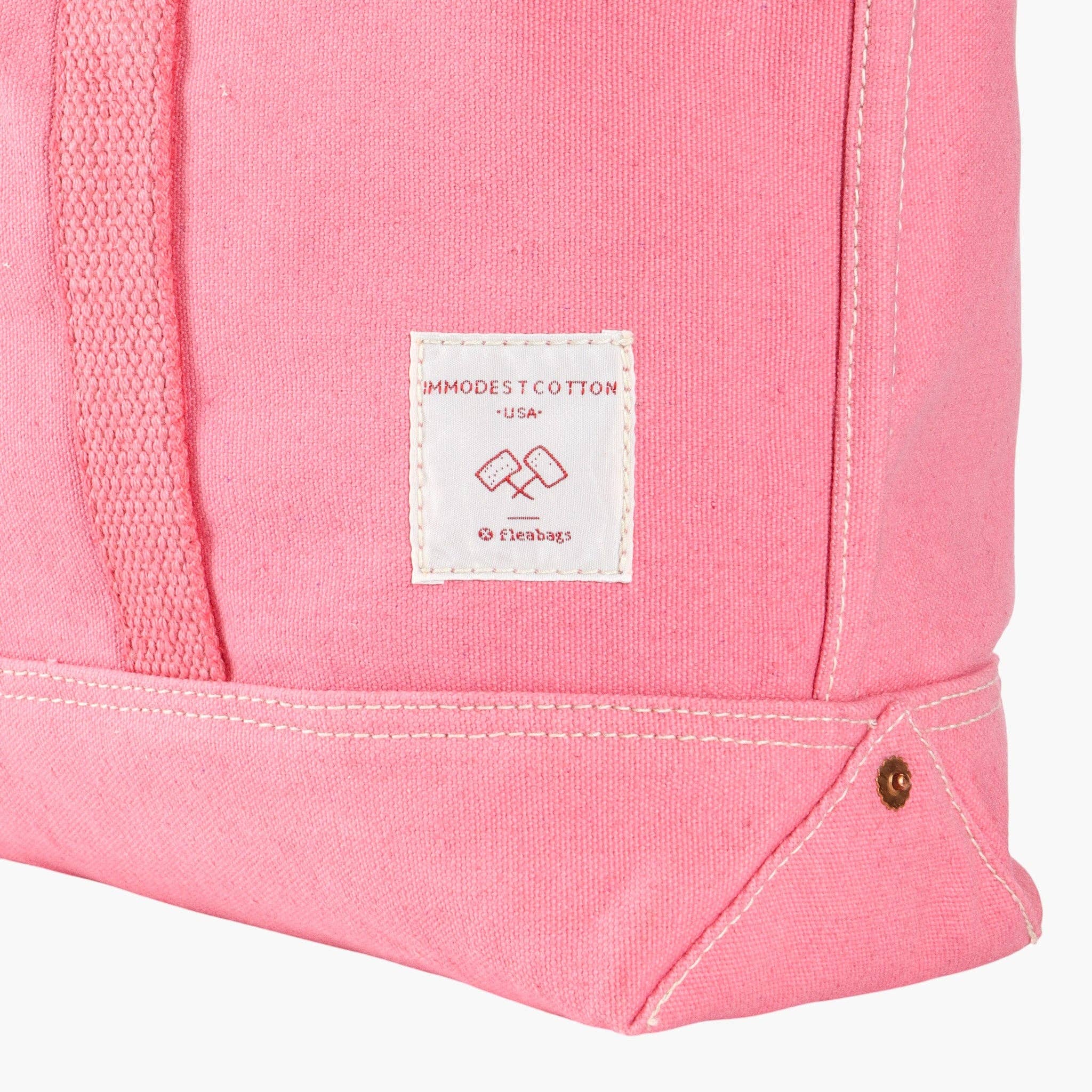 Close-up of pink durable canvas fabric and stitching on Small East West Tote | Flamingo with branded label detail