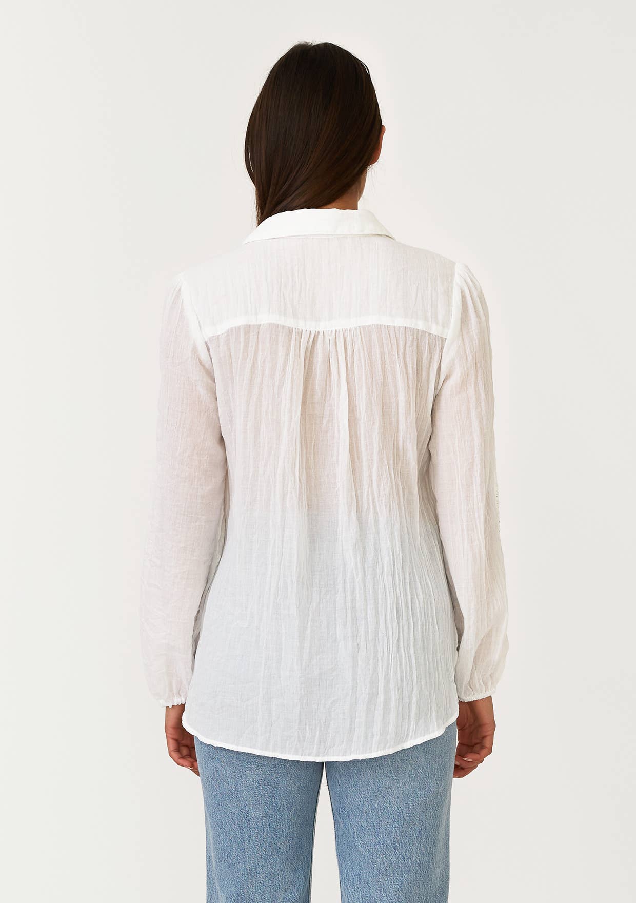 Woman wearing a white Crinkled Lace Long Sleeve Button Down Blouse paired with blue jeans, shown from the back.