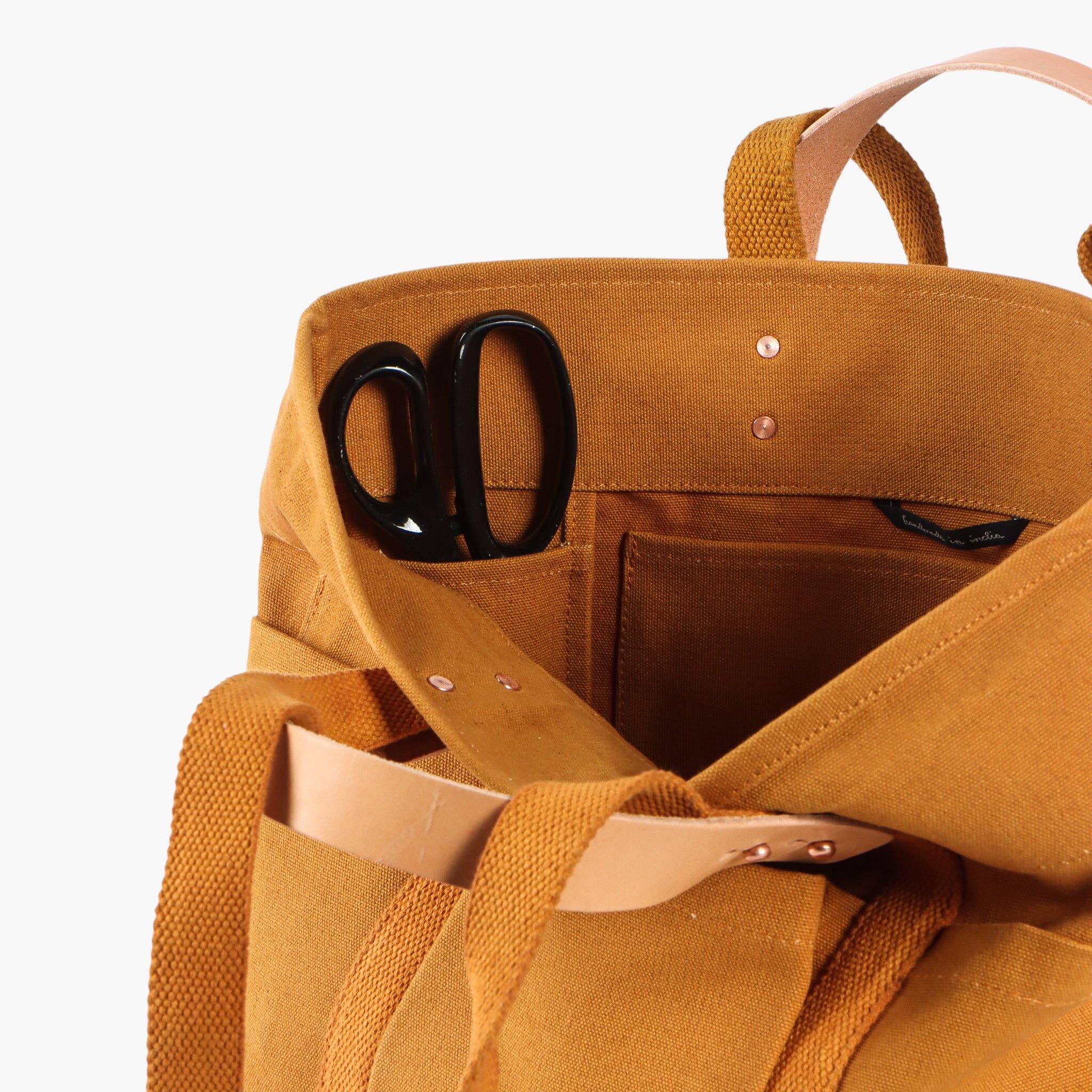 Construction Tote | Mustard Seed with sturdy leather handles and interior pockets holding black scissors on white background