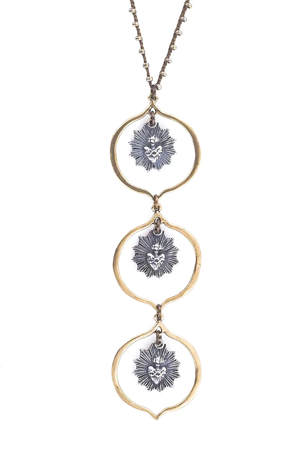 The 32 Sacre Coeur Necklace by Tara Gasparian Jewelry features three vertically aligned gold oval pendants, each with a silver-plated bronze sunburst and central face, hanging from a fine chain against a white background.