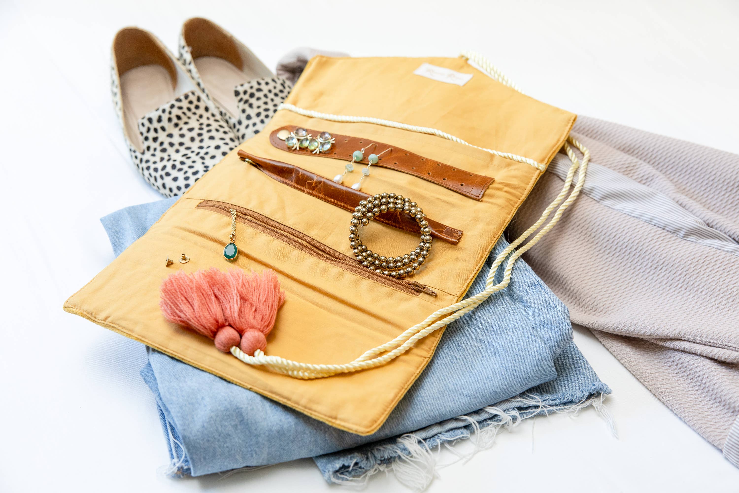 Embroidered Velvet Jewelry Organizer-Mustard laid open with earrings, bracelets, and necklaces on folded clothes and shoes nearby