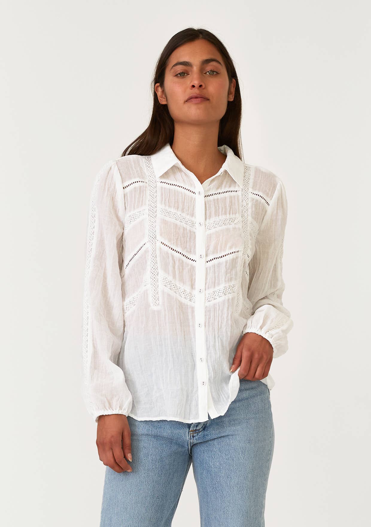 Woman wearing a white Crinkled Lace Long Sleeve Button Down Blouse with delicate lace details and casual blue jeans
