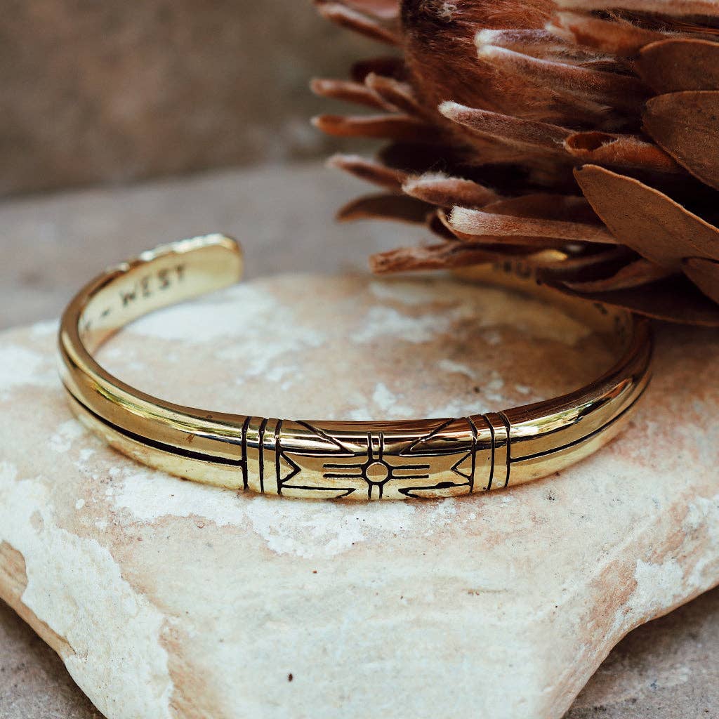 Medicine Wheel Cuff || Men features a polished brass design with engraved artisan graphics on a natural stone surface.