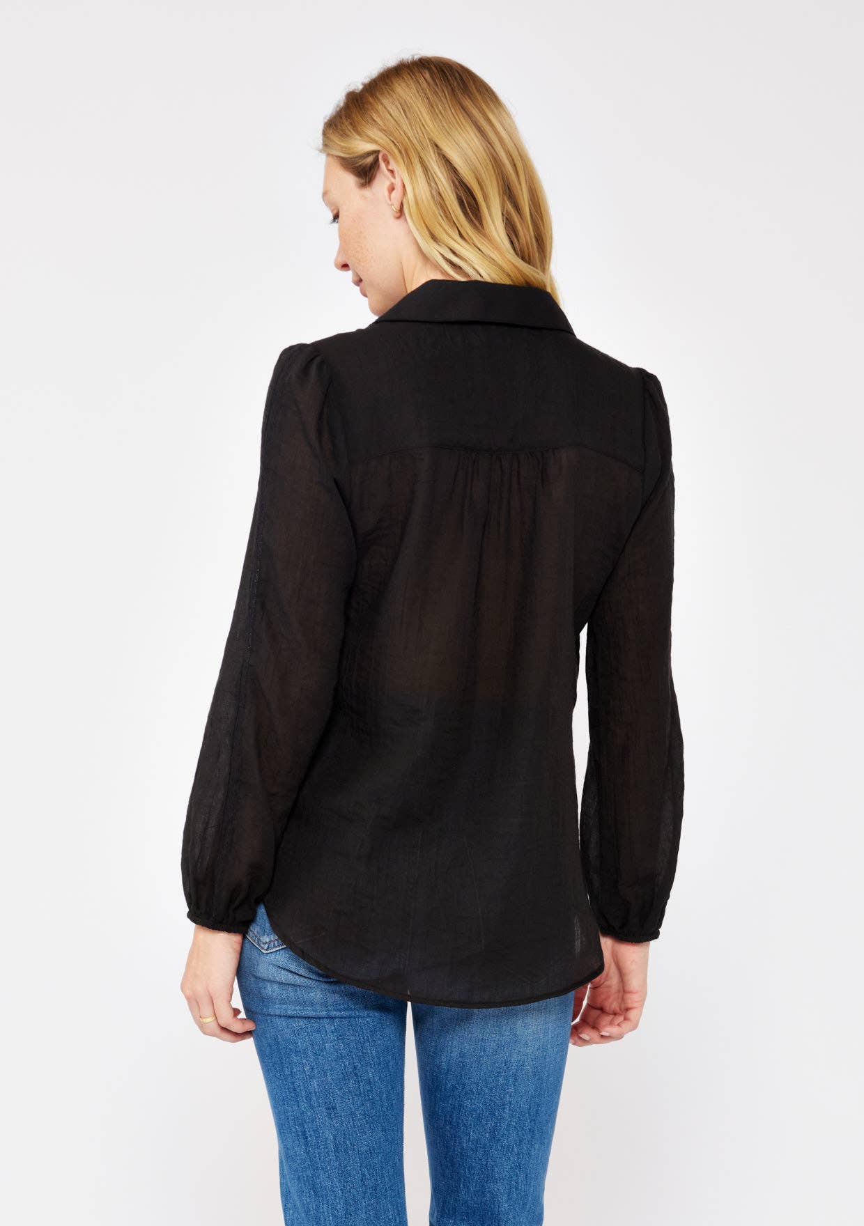 Woman wearing a black Crinkled Lace Long Sleeve Button Down Blouse paired with blue jeans, shown from the back