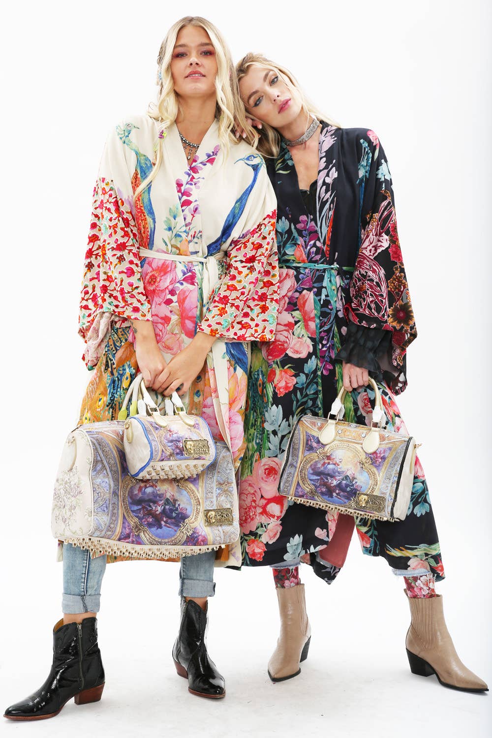 Two women pose against a white background wearing colorful kimonos, including Aratta's Sweet Fantasy Kimono. Each carries a large ornate handbag and wears ankle boots; one rests her head on the other's shoulder.