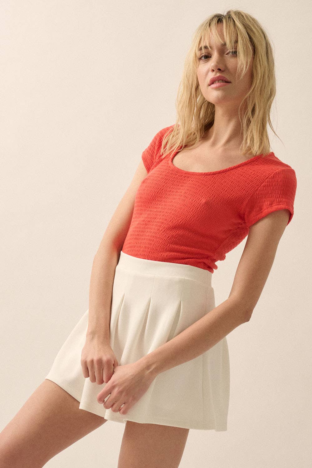 Woman wearing a vibrant red Smocked Jersey Scoop Neck Bodysuit paired with a high-waisted white skirt standing against a plain background