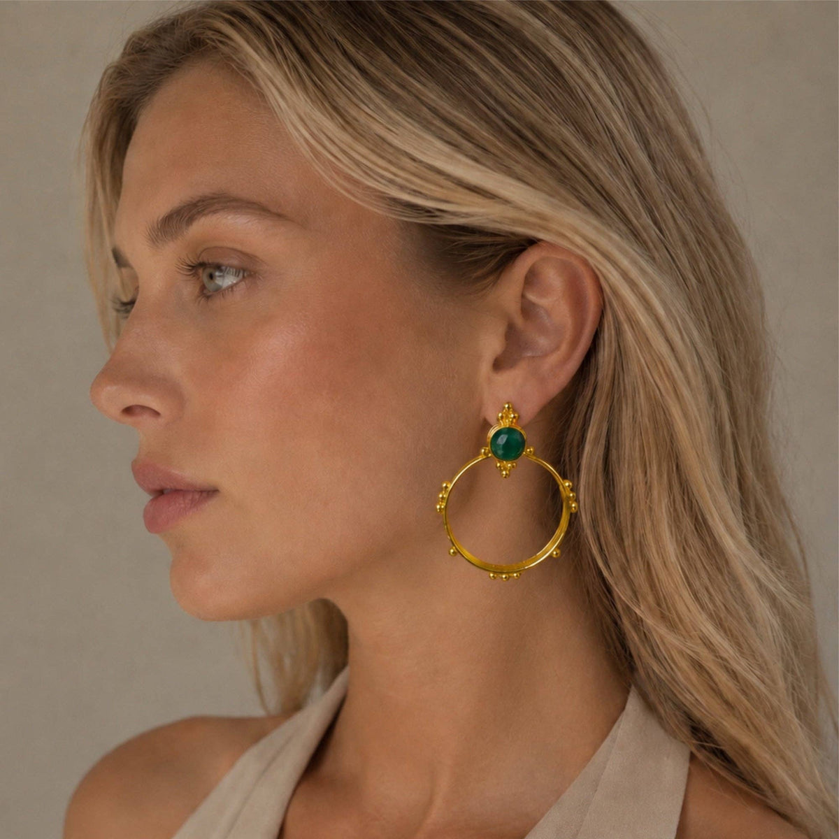 Surya Gold and Emerald Hoops featuring elegant gold hoops with green emerald accents worn on a model