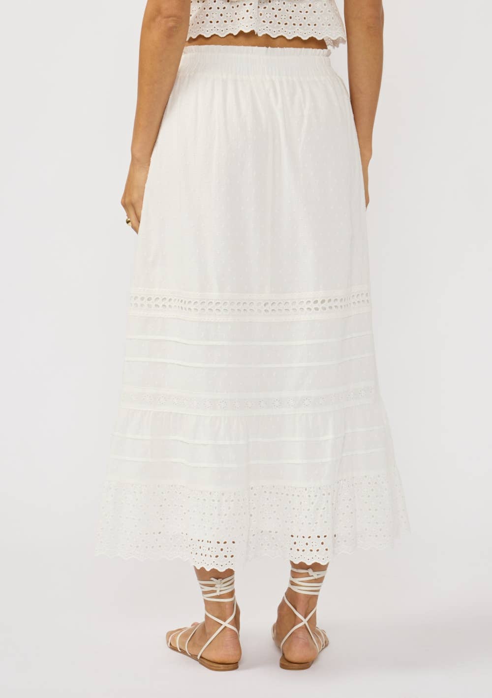 Back view of a white Eyelet Hem Pintuck Skirt featuring delicate eyelet details and a flowing hemline.