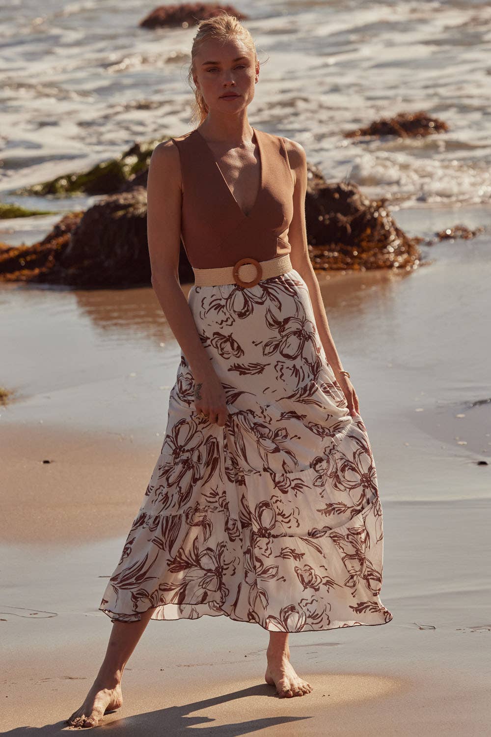 Woman wearing Essential Trends Crepe V-Neck Bodysuit styled with a flowy skirt standing on the beach at sunset